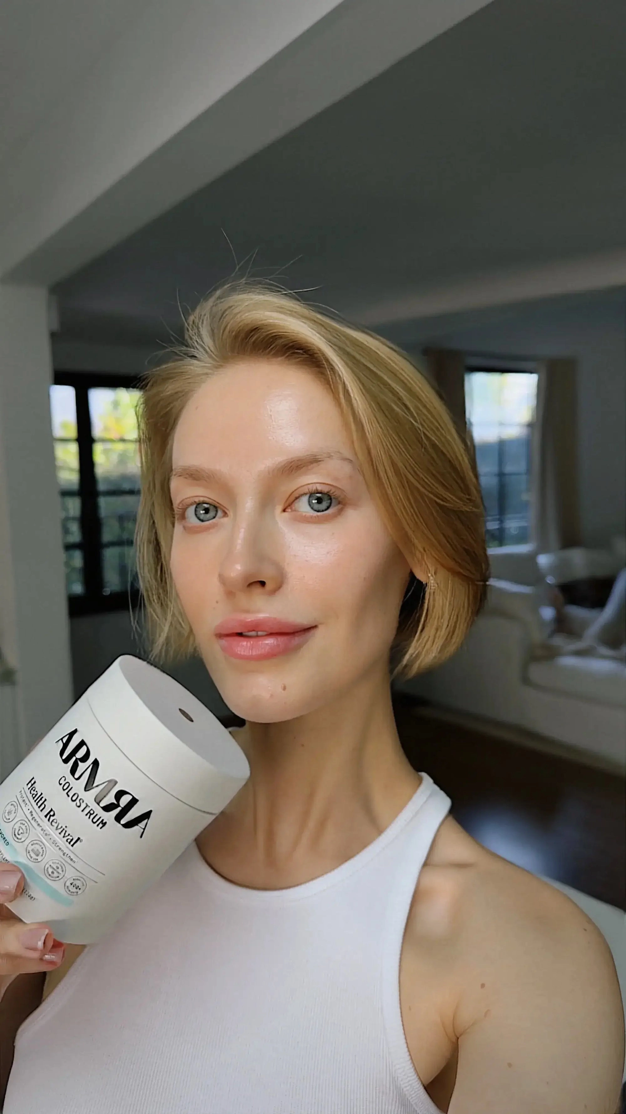 Woman in a white top holding an ARMRA jar