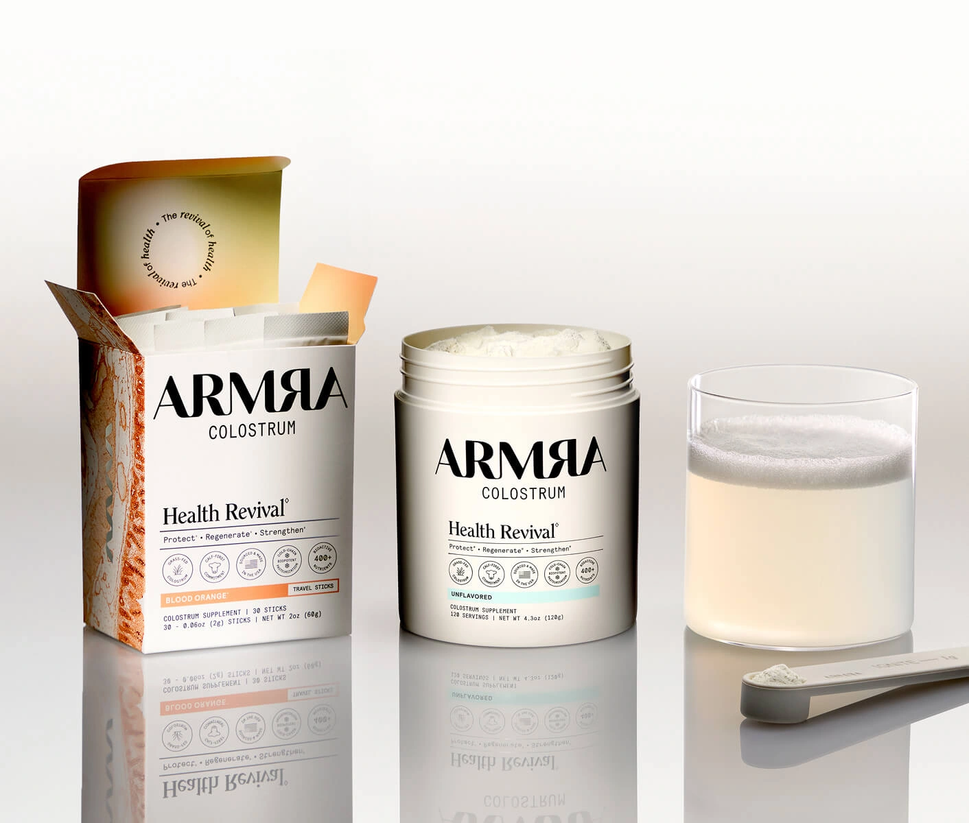 ARMRA Colostrum Travel Sticks box, Unflavored Jar, a glass and a scoop on a reflective surface